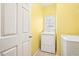 Bright yellow laundry room with white washer and dryer at 306 Blake Dr, Canton, GA 30114