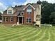 Well-maintained two-story brick home featuring a manicured lawn and complementary siding accents at 1931 Harvest Way, Loganville, GA 30052
