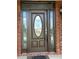 Elegant front door with decorative glass and sidelights, framed by brick columns and covered porch at 1931 Harvest Way, Loganville, GA 30052