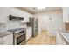 Updated kitchen featuring stainless steel appliances, granite countertops, white cabinets, and wood look flooring at 3815 Glen Laurel Ct, Cumming, GA 30040