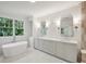 Bright bathroom featuring a soaking tub beneath a window and a double sink vanity with modern fixtures at 114 Terrace Ne Dr, Atlanta, GA 30305