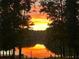A serene lake reflects a vibrant orange sunset framed by lush trees at 25 Clay Ct, Hiram, GA 30141