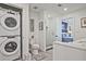 Modern bathroom featuring stacked washer/dryer, toilet, and glass-enclosed shower, flowing into an adjacent bedroom at 788 W Marietta Nw St # 913, Atlanta, GA 30318