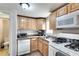Practical kitchen with wood cabinetry, white appliances, and a tiled backsplash at 2312 Wayside Ne Dr, Brookhaven, GA 30319