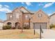 Attractive brick and stone home with a well-maintained lawn, mature tree, and a two-car garage at 4808 Albany Way, Atlanta, GA 30331