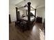 Bedroom featuring a large four-poster bed with detailed carvings, hardwood floors, and traditional furnishings at 10936 Station Dr, Hampton, GA 30228
