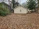 A detached garage is centered in the backyard with a ground covered in leaves at 2921 8Th St, East Point, GA 30344