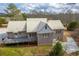 Aerial shot of the rear of the home with a deck, patio, and metal roof amidst a wooded landscape at 550 Oak Ridge Dr, Oxford, GA 30054