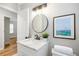 This bathroom includes a marble topped vanity and an elegant black framed round mirror at 2485 Brentwood Rd, Decatur, GA 30032