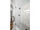 This modern shower features large marble-look tiles, a sleek shower head, and pebble mosaic flooring at 2485 Brentwood Rd, Decatur, GA 30032