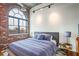 Inviting bedroom featuring a large arched window, exposed brick, hardwood floors and stylish decor at 3235 Roswell Ne Rd # 919, Atlanta, GA 30305