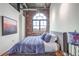 Comfortable bedroom with exposed brick, a large arched window, hardwood floors and stylish decor at 3235 Roswell Ne Rd # 919, Atlanta, GA 30305