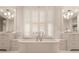 Bright bathroom with soaking tub, window with shutters, dual vanities, and marble countertops at 301 Abercorn Sq, Peachtree City, GA 30269