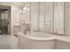 Luxury bathroom featuring soaking tub with window, chandelier, marble countertops, and white cabinetry at 301 Abercorn Sq, Peachtree City, GA 30269