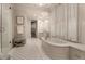 Bright bathroom featuring a soaking tub, chandelier, patterned rug, and window with white shutters at 301 Abercorn Sq, Peachtree City, GA 30269