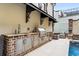 An outdoor kitchen with stainless steel appliances and brick accents, perfect for cooking and entertaining by the pool at 301 Abercorn Sq, Peachtree City, GA 30269