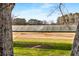 Peeking between the trees, the golf course practice area and safety nets are seen at 2261 Venetian Dr, Atlanta, GA 30311