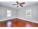 Sunlit bedroom featuring hardwood floors, a ceiling fan, and two windows at 127 Holly St, Social Circle, GA 30025