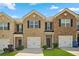 Charming brick townhome featuring a one-car garage, manicured lawn, and inviting front entrance at 815 Taurus Dr, Stockbridge, GA 30281