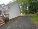 Exterior view of a white home with dark gravel driveway lined with green grass and trees at 525 S Lost Lake Cv, Villa Rica, GA 30180