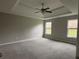 Spacious bedroom featuring tray ceilings, fan with lights, two windows, and plush carpeting at 4976 Notting Glen Ln, Snellville, GA 30039