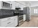 Modern kitchen featuring stainless steel appliances, white cabinets, granite counters, and dark backsplash at 1160 Windsor Pkwy # 13, Atlanta, GA 30319