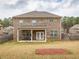 Backyard view of a two-story brick house with a covered patio and a well-maintained lawn at 600 Lockerbie Ter, Mcdonough, GA 30252