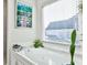 Bright bathroom featuring a large bathtub, window with blinds, and tasteful decorations at 1137 Maple Creek Rdg, Loganville, GA 30052