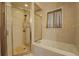 Bright bathroom features a glass-enclosed shower and a large soaking tub with tiled surround and a window at 500 Nicole Se Ct, Conyers, GA 30094