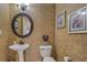 Cozy powder room with patterned wallpaper, pedestal sink, decorative mirror, and framed artwork at 500 Nicole Se Ct, Conyers, GA 30094