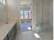 This bathroom features gray cabinets, double sinks, a large mirror, and a walk-in shower with a glass door at 2235 Windsor Bluffs Dr, Cumming, GA 30041