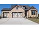 Charming brick home with a three-car garage, striking architectural details, and a concrete driveway at 2235 Windsor Bluffs Dr, Cumming, GA 30041
