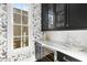 Charming butler's pantry featuring butterfly wallpaper, sleek black cabinets, and a marble countertop with wine fridge at 304 Stonemont Dr, Atlanta, GA 30305