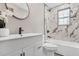 Bright bathroom with white vanity, dark hardware, decorative mirror, and a tub shower combo with marble style tile surround at 1459 Kenilworth Sw Dr, Atlanta, GA 30310