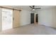 Large bedroom with light carpet, a ceiling fan, and a sliding barn door to the bathroom at 418 Mockingbird, Smyrna, GA 30082