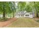 Stunning two-story home with a covered porch, showcasing its white brick and siding amidst a wooded landscape at 418 Mockingbird, Smyrna, GA 30082