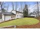 Spacious backyard features lush grass, mature trees, and a stone patio at a white two-story home at 5548 Martina Way, Atlanta, GA 30338