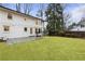 Backyard with a lush lawn, mature trees, stone patio, and white two-story home at 5548 Martina Way, Atlanta, GA 30338