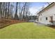 Backyard with a lush lawn, stone patio, and mature trees surrounding a white two-story home at 5548 Martina Way, Atlanta, GA 30338