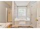 Bathroom featuring separate shower, large tub with jets, decorative wall, and natural lighting at 171 W Fork Way, Temple, GA 30179