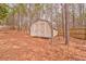 Backyard shed with double doors, providing ample storage space, surrounded by a fence and mature trees at 171 W Fork Way, Temple, GA 30179