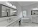 Bright bathroom featuring dual vanities, a standalone tub, tile flooring, and decorative window at 5990 Somerset Ct, Suwanee, GA 30024