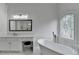 Bright bathroom featuring a standalone tub, vanity area, tile flooring, and decorative window at 5990 Somerset Ct, Suwanee, GA 30024