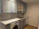 Bright kitchen offers gray cabinetry, marble countertops, stainless sink, and a washing machine at 145 15Th St # Apt 1023, Atlanta, GA 30309