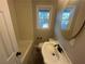 Cozy bathroom featuring a tub with tiled walls and a pedestal sink with a rounded mirror at 185 Nickajack Se Rd, Mableton, GA 30126