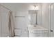 Bright bathroom featuring a shower with neutral curtain, white vanity, and a sleek mirror at 1855 La Dawn Nw Ln, Atlanta, GA 30318