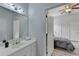 Bright bathroom leading to bedroom, featuring a modern vanity with gold fixtures, contemporary lighting, and a large mirror at 2860 Chardonnay Ln, Cumming, GA 30041