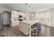 Well-lit kitchen featuring an island with barstool seating, white cabinets, stainless appliances, and hardwood flooring at 6124 Locklear Way, Douglasville, GA 30134