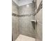 Modern shower featuring gray tile, decorative accent tiles, and a built-in shower caddy for a spa-like experience at 3392 Milan Ct, Douglasville, GA 30135