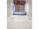 Bathroom featuring a corner tub with a patterned curtain and a decorative valence above at 40 Berkshire Run, Covington, GA 30016